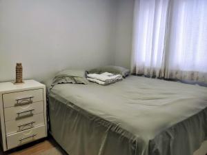 a bedroom with a bed with a dresser and a window at Apartamento Vista Parque in Cascavel