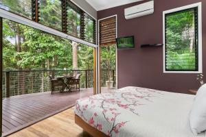 a bedroom with a bed and a balcony with a table at Azabu Retreat & Spa in Byron Bay