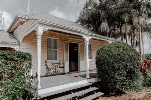 Cette petite maison blanche dispose d'une terrasse couverte et d'une table. dans l'établissement The Postman's Cottage - Hinterland Luxury, à Montville