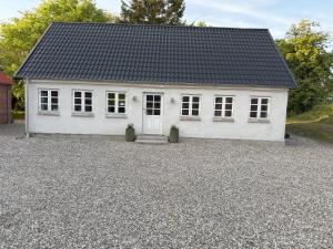 HinnerupRolighed B&B的砾石车道上一座白色房子,屋顶黑色