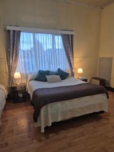 Un dormitorio con una cama con almohadas azules y una ventana. en alojamiento en punta arenas, en Punta Arenas