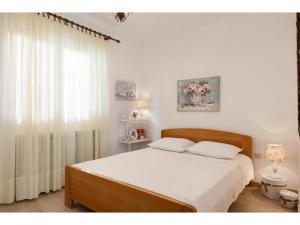 een slaapkamer met een bed met witte lakens en een raam bij Holiday Home Vallis in Povlja