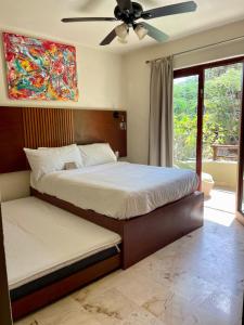une chambre avec deux lits et un ventilateur de plafond dans l'établissement 2BR Kobah 1 Block to Beach & 5th Pool Gym, à Tulum