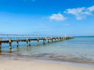 a pier in the water next to a beach at Ferienwohnung Sonnenplatz Moba-Travel in Travemünde +4 photos