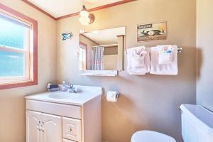 une salle de bain avec un lavabo, des toilettes et un miroir dans l'établissement Anchorage Cottages #1, à Long Beach