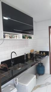 eine Küche mit einem Waschbecken und einer schwarzen Arbeitsplatte in der Unterkunft Festa de São João cg in Campina Grande
