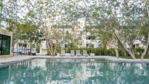 ein Pool mit Stühlen und Bäumen sowie ein Gebäude in der Unterkunft Beautiful House in Playa del Carmen in Playa del Carmen