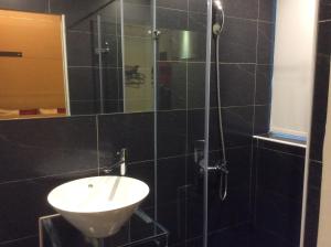 a black tiled bathroom with a sink and a shower at 紫園旅社Purple Garden Hotel in Taipei