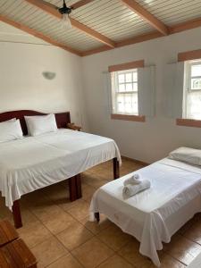 a bedroom with two beds and two windows at Pousada Pouso do Sô Vigario in Pirenópolis