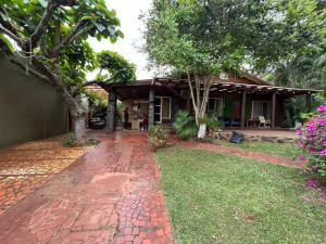 a house with a brick walkway in front of a yard at Tucan Hostel in Puerto Iguazú