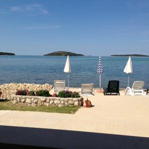 a beach with chairs and umbrellas and the ocean at Seaside house for families with children Krapanj, Sibenik - 24166 in Šibenik