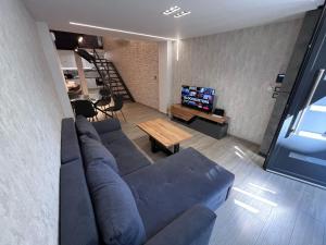 a living room with a blue couch and a tv at Loft of e-smile in Thessaloniki