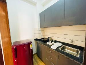 a small kitchen with a sink and a red refrigerator at The Empire Stays , Golf Course Road in Gurgaon