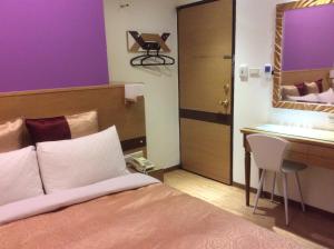 Schlafzimmer mit einem Bett, einem Schreibtisch und einem Spiegel in der Unterkunft 紫園旅社Purple Garden Hotel in Taipeh
