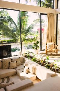 a living room with white furniture and large windows at Ubud Dzen Villa 8 in Ubud
