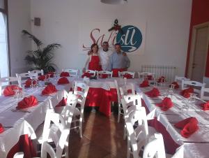 a group of people standing around a long table with red flowers at Salisù Country House in Mignano Monte Lungo