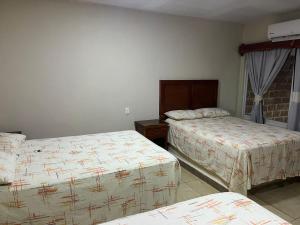 a hotel room with two beds and a window at Hotel y Restaurante La Montaña in Mapastepec