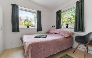 a bedroom with a pink bed and two windows at 2 Bedroom Gorgeous Home In Gilleleje in Gilleleje