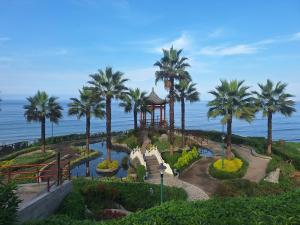 a garden with palm trees and a gazebo next to the ocean at Room in shared apartment - Shared Bathroom 402 in Lima