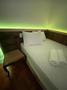 a small bed with two pillows and a chair at Kitnet compacta in Salvador