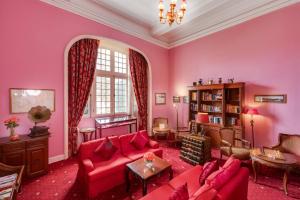 a living room with pink walls and red furniture at Dalat Palace Heritage Hotel in Da Lat