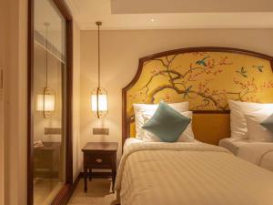 归仁FLC Sea Tower QUY NHƠN-Khách Sạn 5 Sao-Hồ Bơi-View Biển-Trung Tâm Tp的一间卧室，有两张床和一幅树壁画 更多32张照片