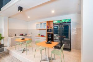 a kitchen with two tables and chairs and a refrigerator at Bali Loop Coliving & Coworking in Denpasar