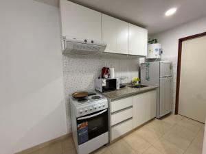 a kitchen with white cabinets and a stove and refrigerator at Departamento Céntrico San Martín in San Martín