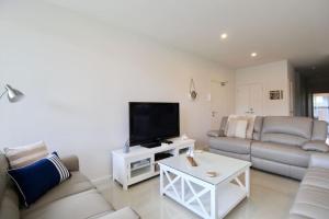 Una sala de estar con un sofá y un televisor. en Avalon Apartment - 1 Bedroom, en Huskisson