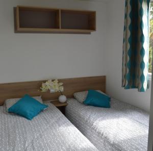 two beds with blue pillows in a bedroom at Beau mobilhome La Palmyre 4 étoiles in Les Mathes