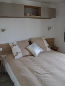 a bed with two pillows on top of it at Beau mobilhome La Palmyre 4 étoiles in Les Mathes