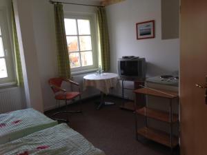 Zimmer mit einem Bett, einem Tisch und einem TV in der Unterkunft Landgasthaus am Dolgensee in Reichenwalde
