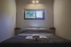 a bed with two towels on it with a window at Refugio del Hornero Norte in San Carlos de Bariloche