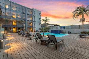 a building with a deck with chairs and a swimming pool at Beach Getaway in Mount Maunganui