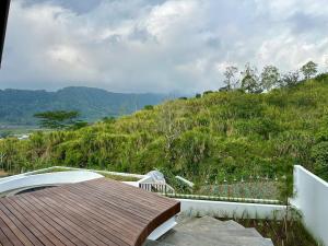a wooden deck with a view of a hill at DELIMA A Frame House in Singaraja