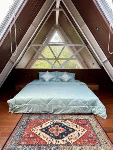 シンガラジャにあるDELIMA A Frame Houseの大きな窓のある屋根裏部屋のベッド