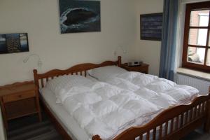 une chambre avec un grand lit blanc et une fenêtre dans l'établissement Marschenblick-1, à Sankt Peter-Ording