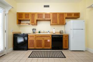 a kitchen with wooden cabinets and a white refrigerator at Be A Nomad - Pool - 1bdr Just 1 Block to the Beach in Jacksonville Beach +12 photos