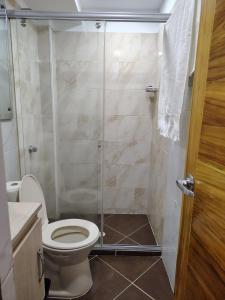 um banheiro com vaso sanitário e box de vidro em Acojedor apto en coveñas em Coveñas