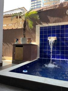 a blue tiled pool with a water fountain at Casa Ferry Piscina Privativa e Hidro 300m da Praia in Praia Grande