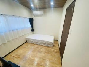 um pequeno quarto com uma cama e uma janela em 時間を忘れる貸別荘オールブルー em Hiroshima