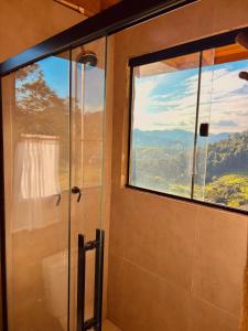 a bathroom with a shower with a large window at Cabana Serra do Vento in Passa Quatro