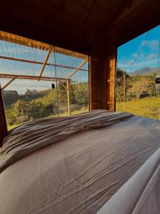 a bed in a room with a large window at Cabana Serra do Vento in Passa Quatro