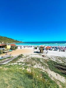 a beach with umbrellas and people on the sand at Hospedatom - Apartamento Beira-Mar Praia Grande Arraial do Cabo in Arraial do Cabo