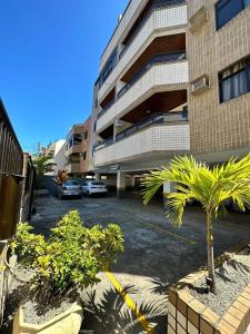 アハイアウ・ド・カボにあるHospedatom - Apartamento Economy Prainha Arraial do Caboのヤシの木の建物前の駐車場 +10枚の写真