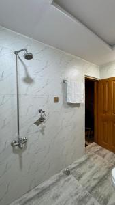 Un baño con ducha con paredes de mármol blanco. en Cozy One-Bed Studio Retreat, en Rawalpindi