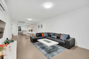a living room with a black leather couch and a table at Sub-Penthouse with Marina View by Host Solutions in Glenelg