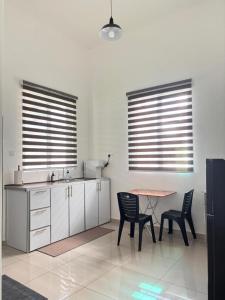 Il comprend une cuisine avec une table et des chaises ainsi que 2 fenêtres. dans l'établissement Olive Homestay SP Saujana 5 Bedrooms 6 Toilets Mus lim Friendly, à Sungai Petani