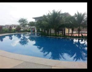 a large blue swimming pool with palm trees in the background at DhiyaAdraHomestay in Chemor
