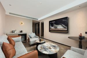 成都市にあるAtour S Hotel Chengdu Huaxi Provincial Stadium Metro Stationのソファと壁掛けテレビのあるリビングルーム